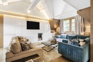 A modern living room with a beige sofa, a blue sofa, a glass coffee table, and a flat-screen TV mounted on the wall. - Mayfair Home Central AC Huge Terrace (London)