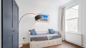 A room with a white bed, a picture on the wall, a window, and a door. - Luxury Modern 5-bed Home Maida Vale (London)