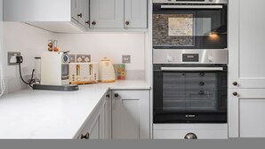 A kitchen with white cabinets, a Bosch oven, a toaster, and a coffee maker. - Luxury Modern 5-bed Home Maida Vale (London)