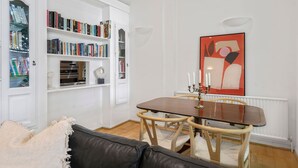 A dining area with a wooden table and chairs, a bookshelf filled with books, and a modern abstract painting on the wall. - 2-bed Knightsbridge Home (London)