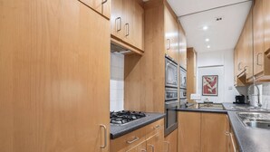 A modern kitchen with wooden cabinets, stainless steel appliances, and a granite countertop. - 2-bed Knightsbridge Home (London)
