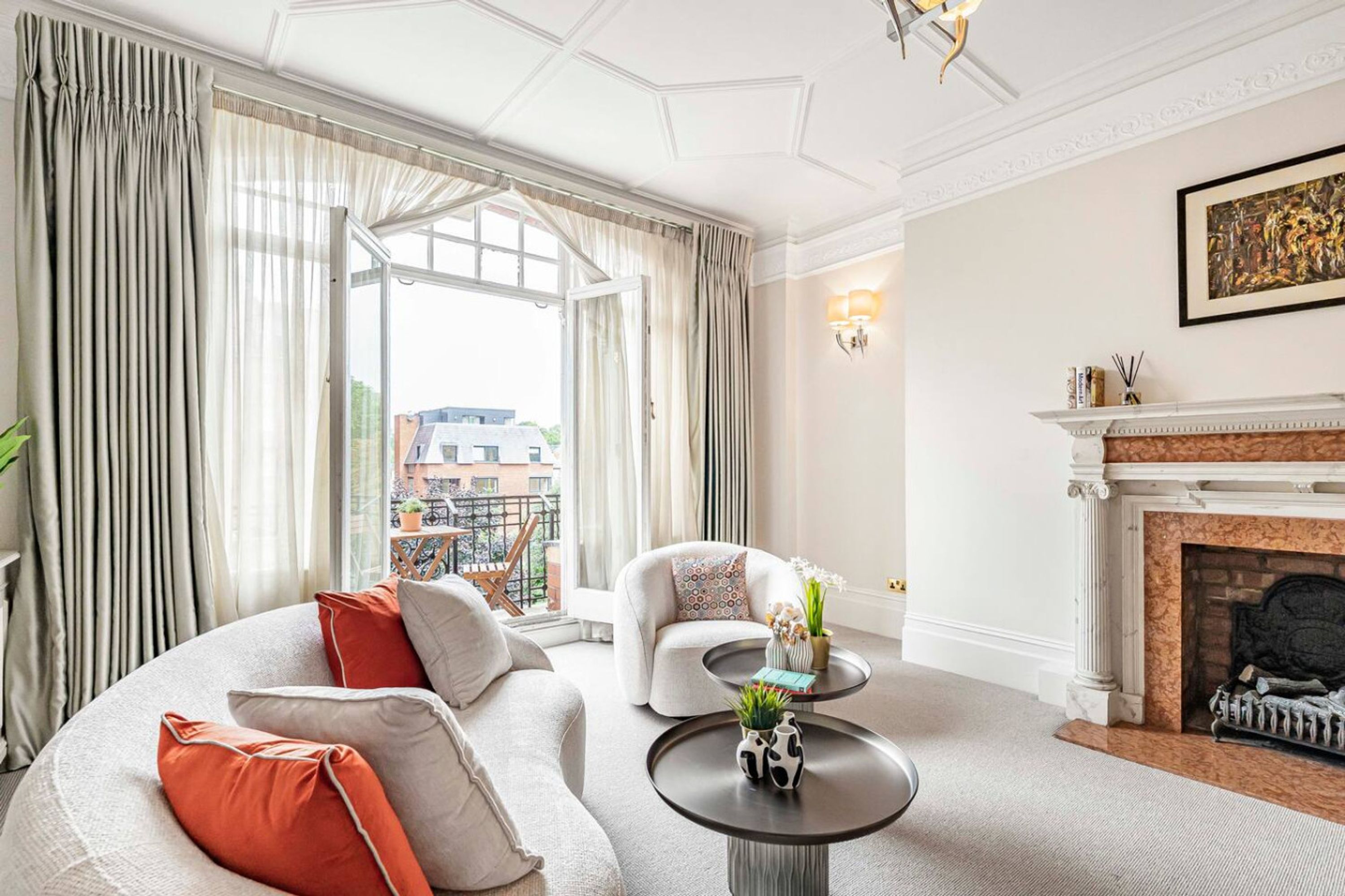 A spacious living room with a large window, a fireplace, and a round coffee table.