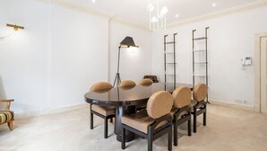 A conference room with a round table, six chairs, a standing lamp, and a chandelier. - Luxury 3BR Mayfair Apartment Near Green Park (London)
