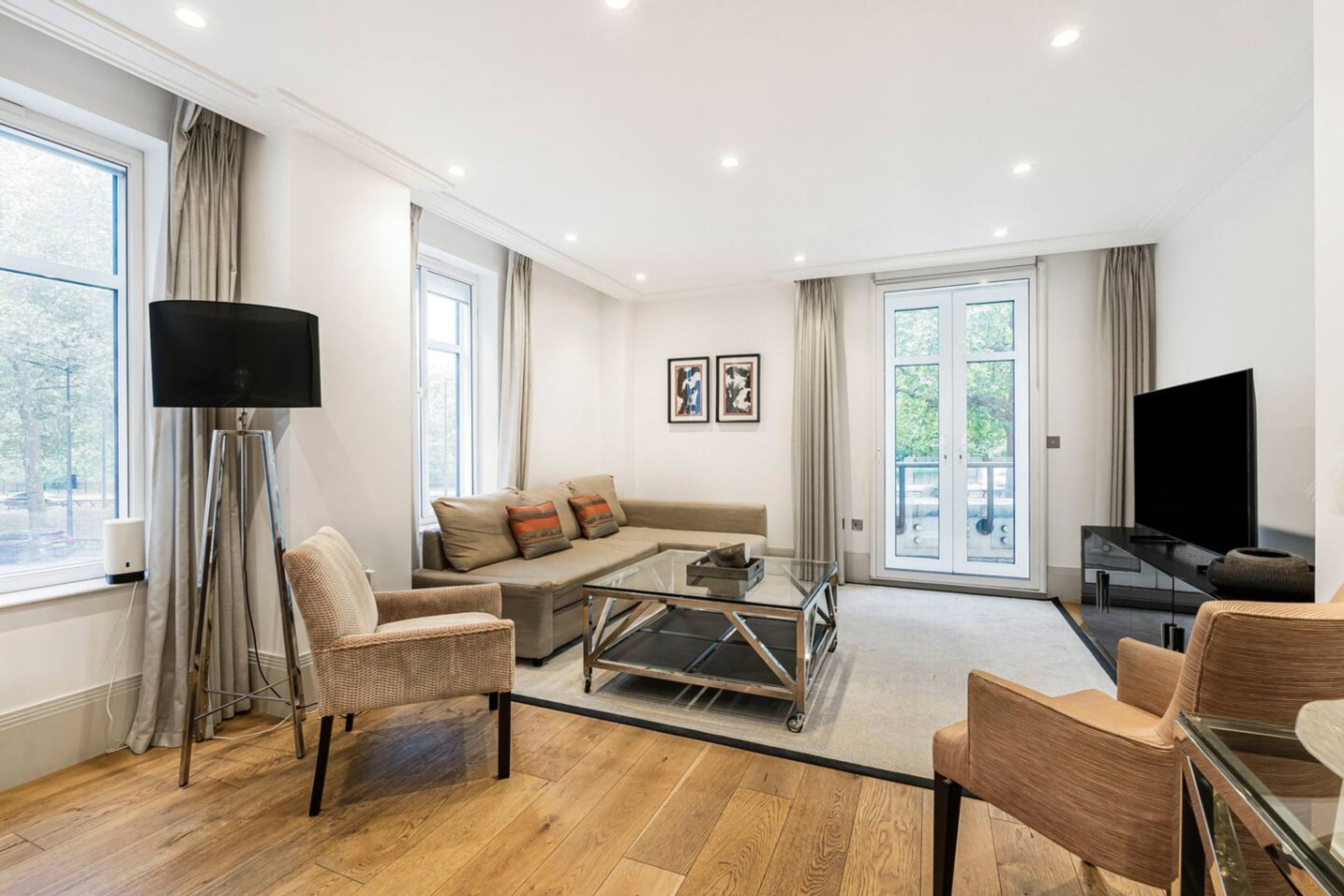 A modern living room with a sofa, armchairs, a coffee table, and a TV.