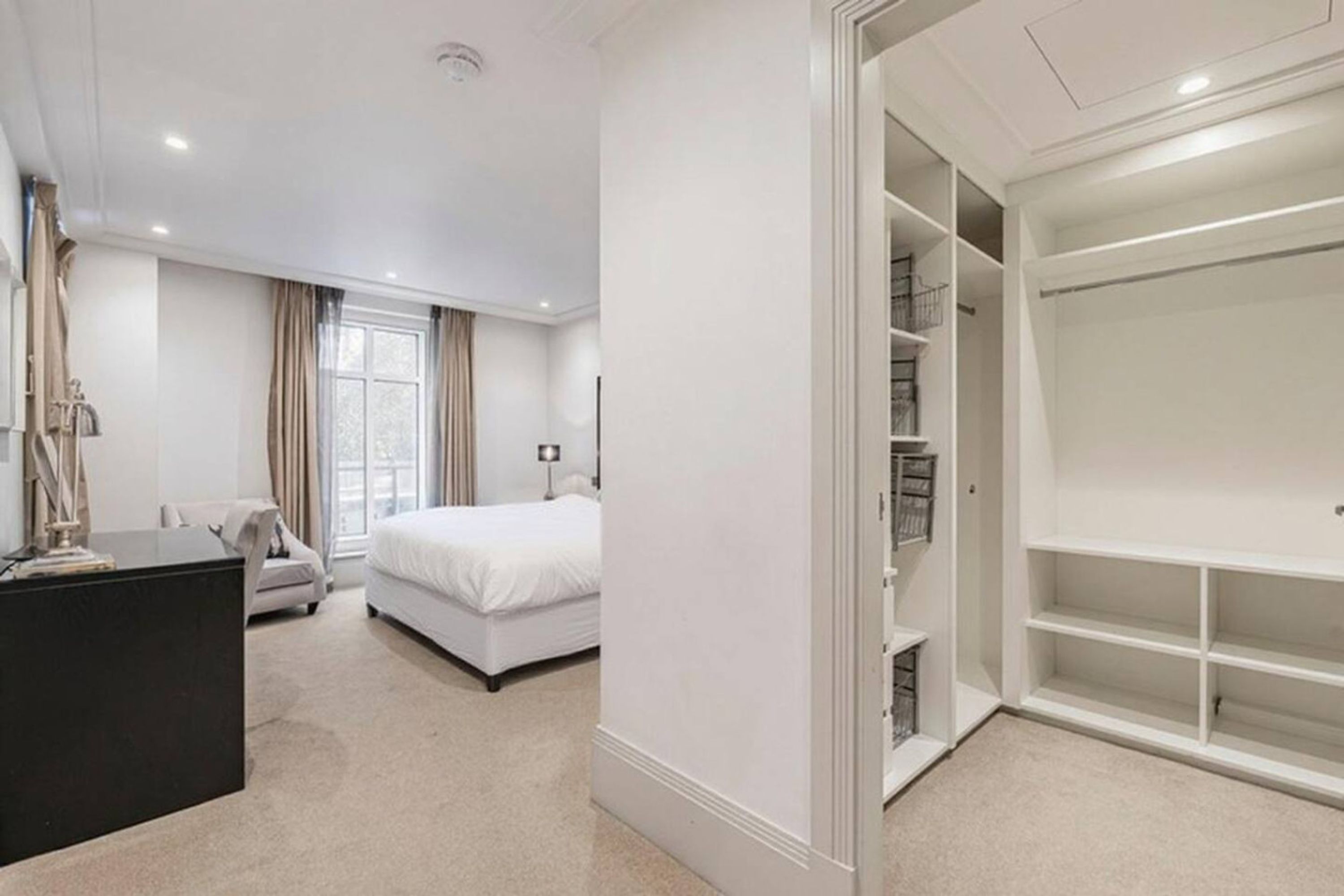 Ein Schlafzimmer mit Bett, Schreibtisch und begehbarem Kleiderschrank.