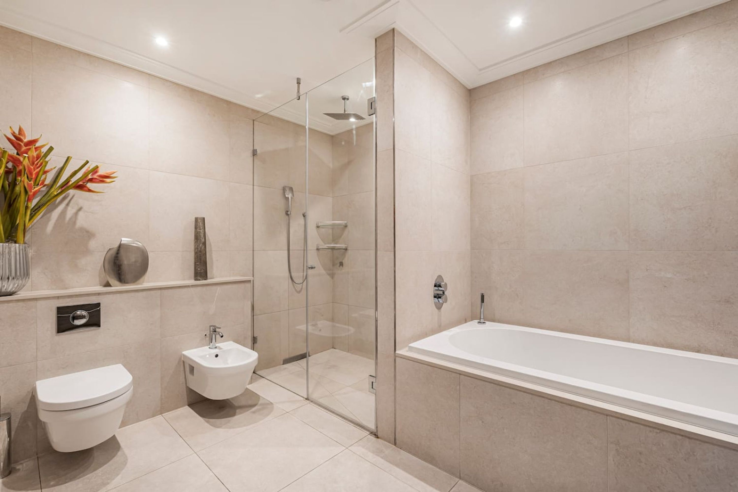 A modern bathroom with a bathtub, toilet, and bidet.