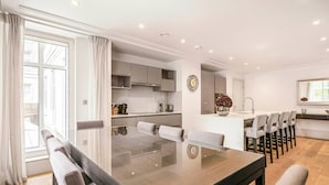 Une cuisine moderne avec des meubles de couleur grise, un îlot central doté de tabourets de bar et une grande table à manger.
