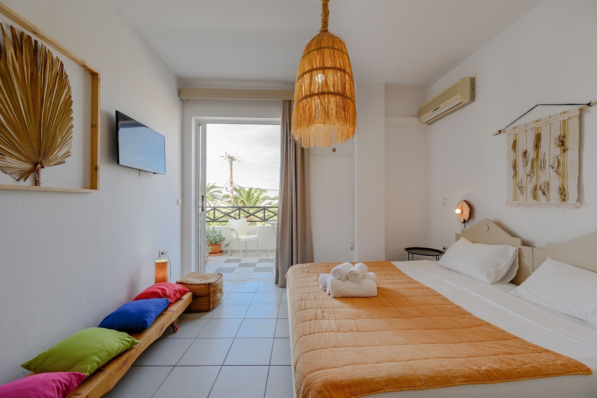 Habitación de hotel con cama, televisión, ventilador de techo y vistas al exterior.