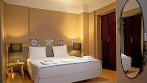 Een netjes ingerichte hotelkamer met een groot bed, bedlampen, een klein tafeltje en een spiegel.