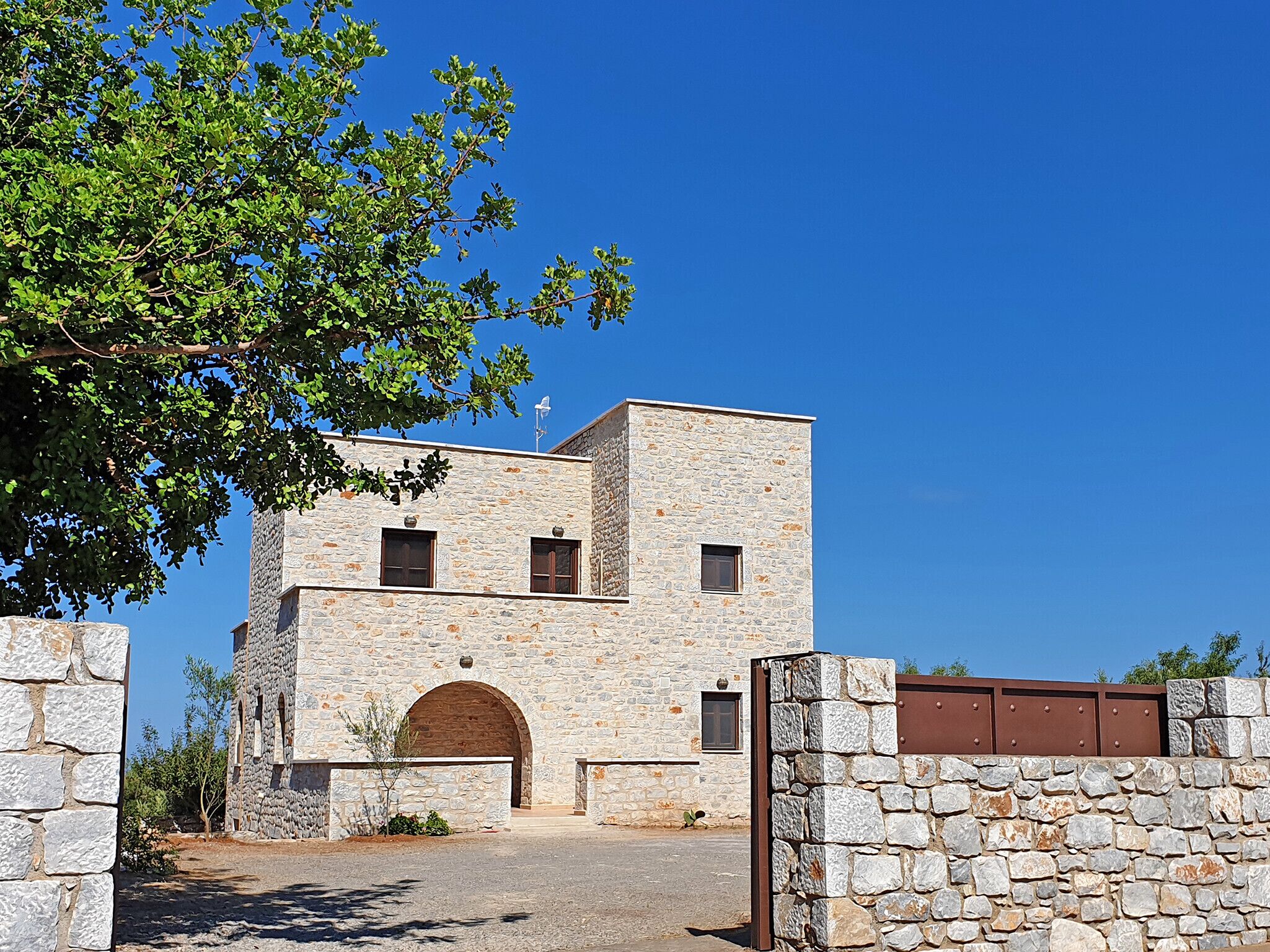 Un edificio in pietra con un ingresso centrale ad arco, un tetto piatto e una piccola finestra al piano superiore.