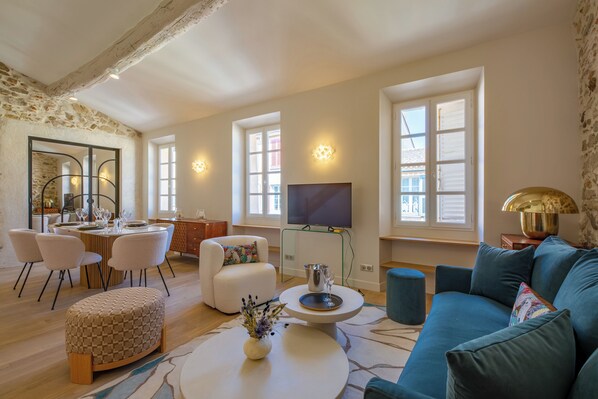 A modern living room with a dining area, a sofa, a TV, and a large window. - Charming apartment in heart of Saint-Tropez - 4 guests (Saint-Tropez)