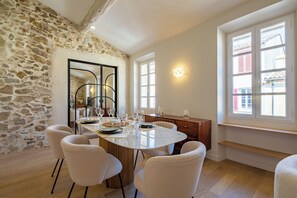 A dining area with a stone wall, a round table, and six chairs. - Charming apartment in heart of Saint-Tropez - 4 guests (Saint-Tropez)