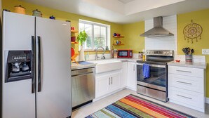 A modern kitchen with stainless steel appliances, white cabinetry, a colorful striped rug, and a window providing natural light. - Sip, Hike, Relax! Cottonwood Home 4 Mi to Old Town (Cottonwood)