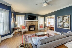 A living room with a fireplace, sofas, a television, and a ceiling fan.