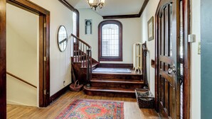 Una imponente escalera de madera con candelabro, que conduce a un rellano con un amplio ventanal.