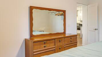 A bedroom with a wooden dresser, a large mirror, and a bed.