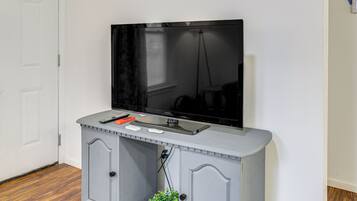 A television mounted on a grey cabinet with a remote control and a mouse on top.