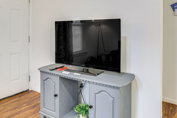 Ein Fernseher, der an einem grauen Schrank befestigt ist, mit Fernbedienung und Maus darauf.