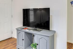 Un televisor montado en un mueble gris con un control remoto y un ratón encima.