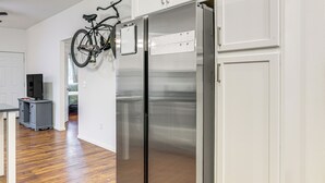 Moderni keittiö, jossa on ruostumattomasta teräksestä valmistetut kodinkoneet, puulattia ja seinälle kiinnitetty polkupyörä.