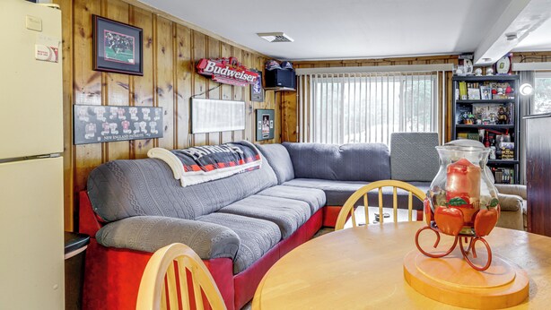 Un salon confortable avec un canapé, une table en bois et un réfrigérateur.