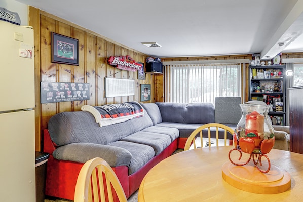 Ein gemütliches Wohnzimmer mit einer Couch, einem Holztisch und einem Kühlschrank.