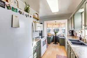 A kitchen with a refrigerator, stove, microwave, and sink. There is a window with curtains and a plant on the counter. - Updated & Charming! Waterloo Home w/ Patio (Waterloo)