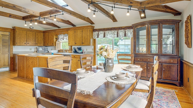 A spacious kitchen with wooden cabinets, a dining table set for four, and a large wooden cabinet with glass doors. - Walk to Dtwn Warsaw: Family Home w/ Deck! (Warsaw)