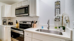 Una cucina moderna con mobili bianchi, elettrodomestici in acciaio inossidabile e un elemento decorativo a parete.