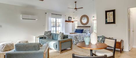 A spacious living room with a sofa, a dining table, and a ceiling fan.