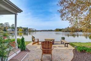 Une terrasse avec des meubles d’extérieur, un espace salon abrité et une vue sur un lac.