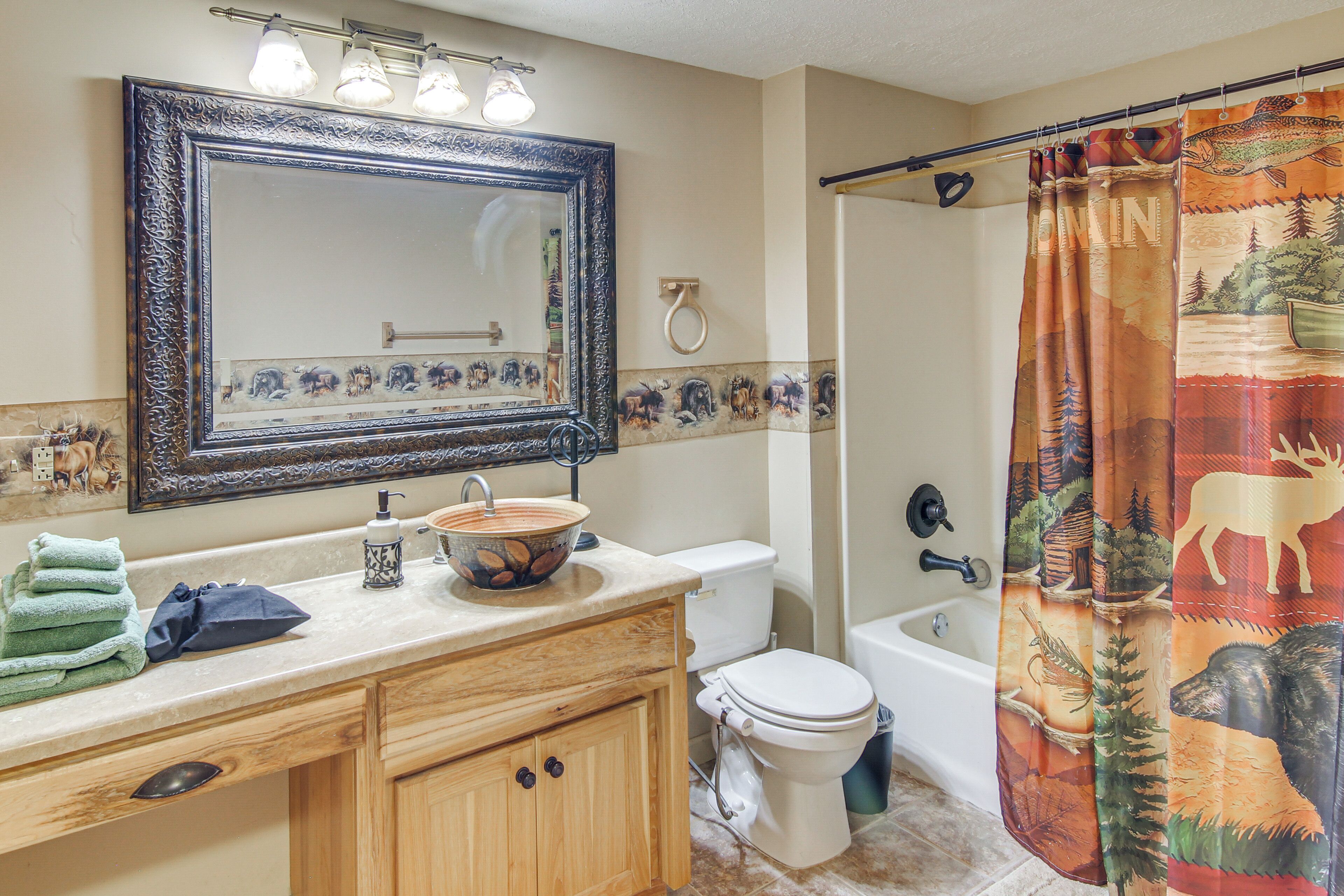 A bathroom with a sink, mirror, toilet, and bathtub.