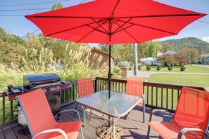 A deck with a barbecue grill, a glass table, and red chairs. - Trail Town Usa! 2BD Cabin on Laurel Creek w/ Deck (Damascus)