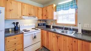 A kitchen with wooden cabinets, a stove, a microwave, and a sink. - Trail Town Usa! 2BD Cabin on Laurel Creek w/ Deck (Damascus)