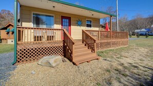 A two-story building with a wooden deck, a red door, and a sun decoration on the wall.