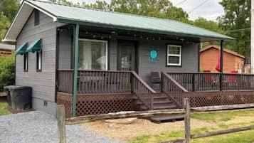 A two-story building with a porch, a fenced yard, and a small shed in the background.