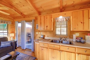Interior de una cabaña de madera con cocina, comedor y sala de estar.