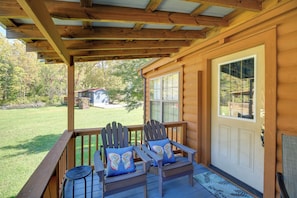 A wooden porch with two Adirondack chairs and a bench, a door with a window, and a view of a house and trees in the background. - Pet-friendly Damascus Cabin w/ Deck & Mtn Views! (Damascus)