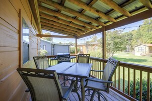 Un patio techado al aire libre con mesa y sillas, una parrilla y vistas a una zona residencial.