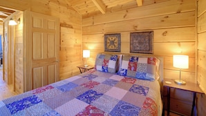 Un dormitorio de cabaña de madera con una cama grande, dos lámparas de pared y una puerta.