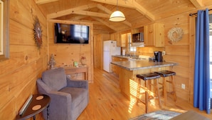 Una cabaña de madera acogedora con sala de estar, cocina y zona de bar.