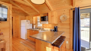 Cocina de cabaña de madera con refrigerador, estufa, microondas y una isla grande con asientos.