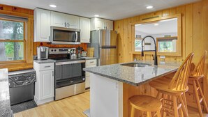 A modern kitchen with white cabinets, stainless steel appliances, and a granite countertop. - Ludlow Cabin on Lake Pauline w/ Outdoor Fire Pit (Ludlow)