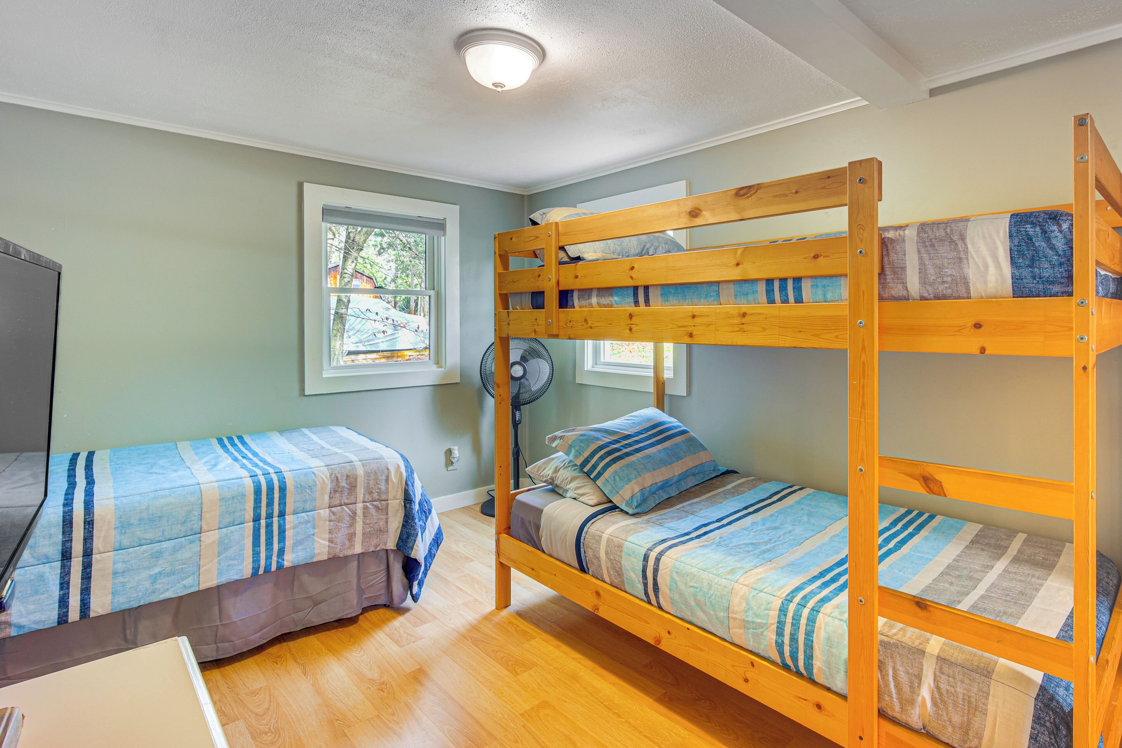 A bunk bed room with two beds, a fan, and a window.