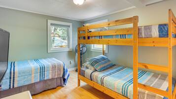 A bunk bed room with two beds, a fan, and a window.