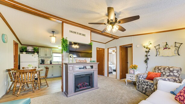 A cozy living room with a fireplace, a dining area, and a kitchen in the background. - Walk to Houghton Lake! Family Retreat w/ Patio (Houghton Lake Heights)