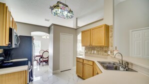 A modern kitchen with wooden cabinets, a stainless steel sink, and a decorative stained glass light fixture. - Spacious Home w/ Yard: 8 Mi to Wabasso Beach (Sebastian)