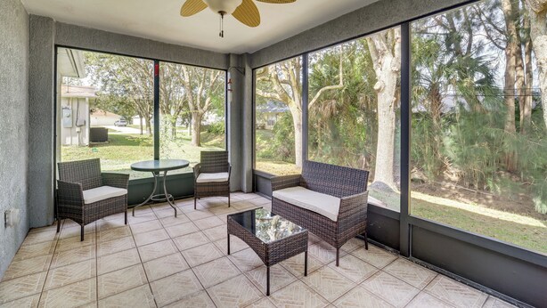 A sunroom with wicker furniture, large windows, and a ceiling fan. - Spacious Home w/ Yard: 8 Mi to Wabasso Beach (Sebastian)