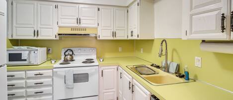 A kitchen with white cabinets, a microwave, an oven, a sink, and a dishwasher.