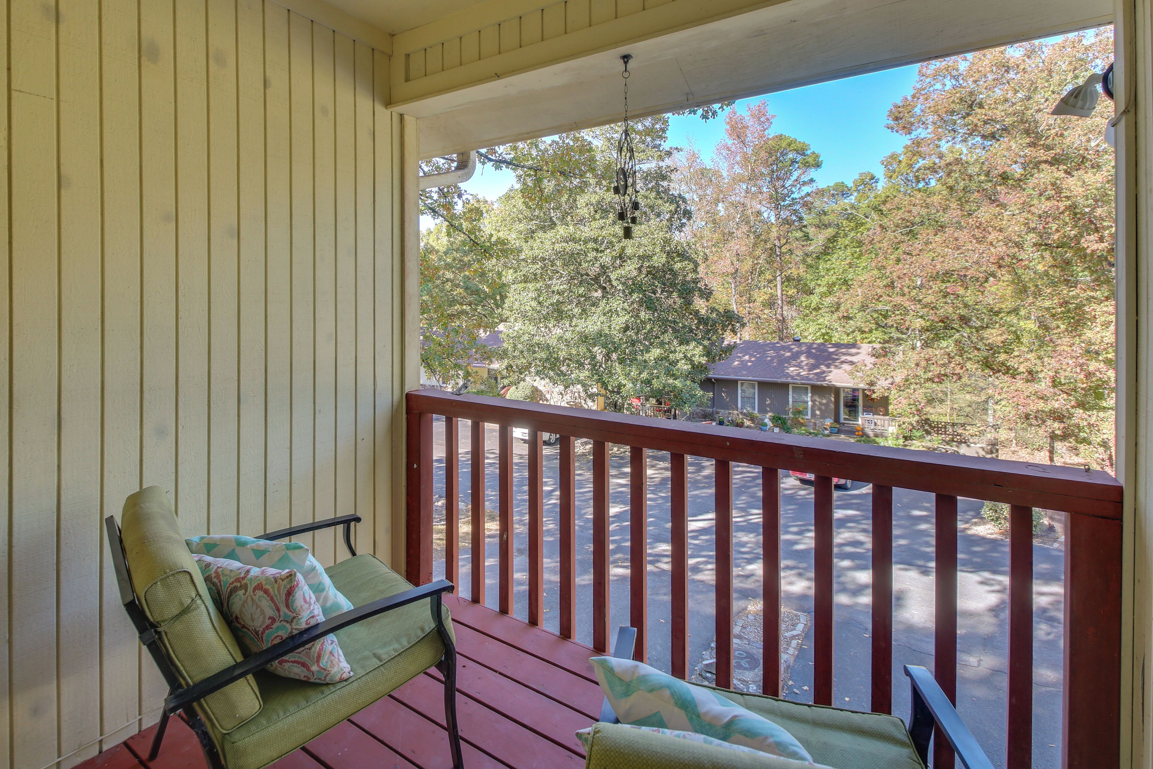 A porch with a wooden railing, a green chair, and a cushion.